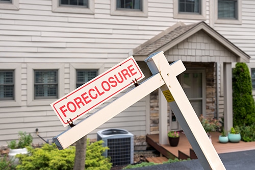 Mockup of a foreclosure sign in front of a modern townhome or townhouse to illustrate recession fears due to coronavirus